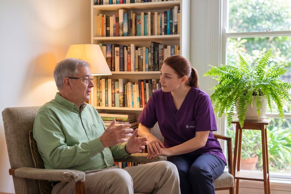 An older man talking with a support worker in his living room.