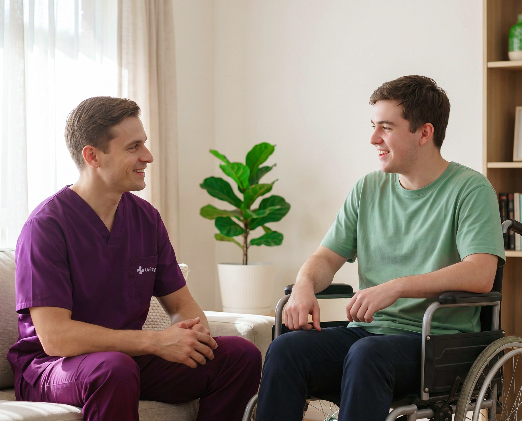 A support worker sitting and talking with a young man who uses a wheelchair.